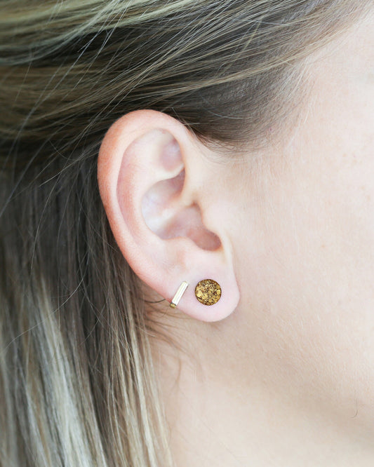 Close-up of an ear wearing a gold earring with a gemstone.