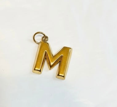 Gold letter M pendant charm on white background, minimalist jewelry accessory