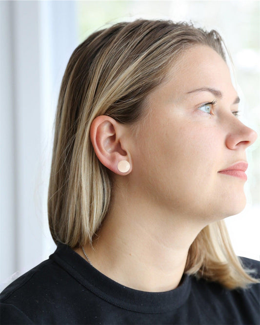Woman wearing minimalist round stud earrings, handmade jewelry close-up