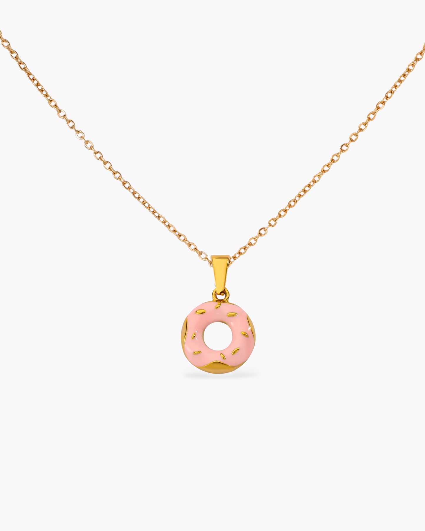 Gold chain necklace with a pink donut-shaped pendant and sprinkle accents, minimalist jewelry