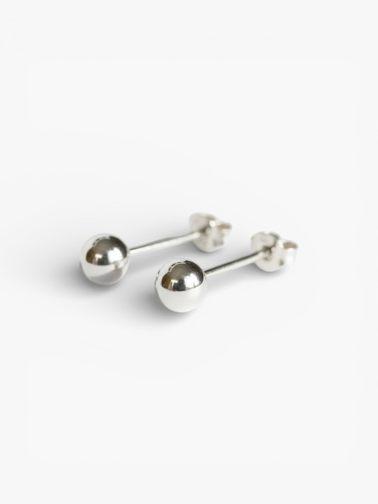 Minimalist silver ball stud earrings on white background, handmade jewelry