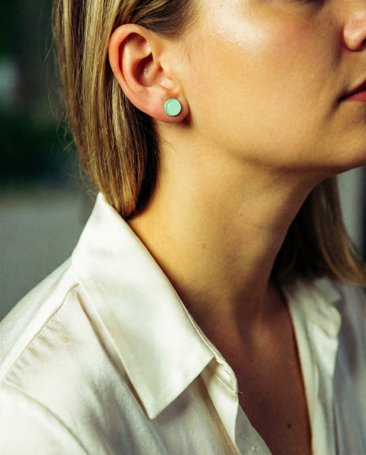 Woman wearing mint green minimalist stud earring, close-up on ear and earring