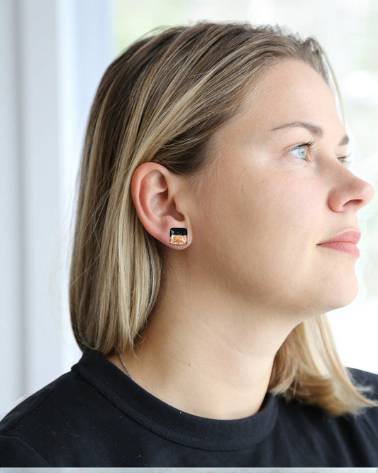Woman wearing minimalist black square stud earrings, handmade jewelry close-up