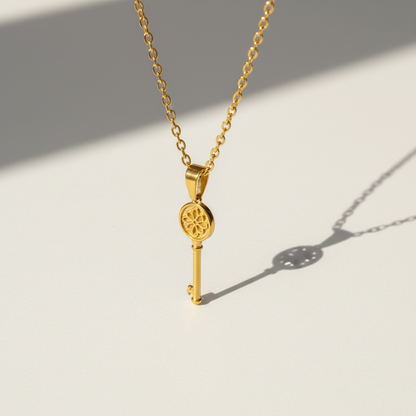 Gold key pendant necklace with floral detail on minimalist chain