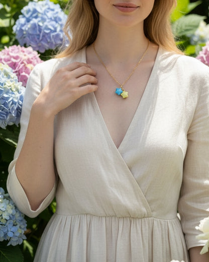 Woman wearing handmade pastel star necklace in garden with blooming hydrangeas