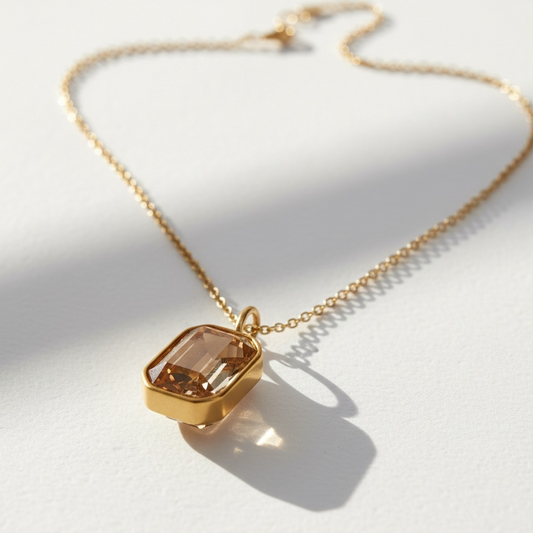 Gold necklace with a rectangular pendant on a white background