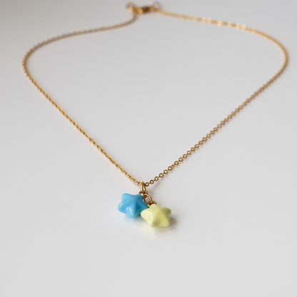 Gold chain necklace with blue and yellow star-shaped charms on white background