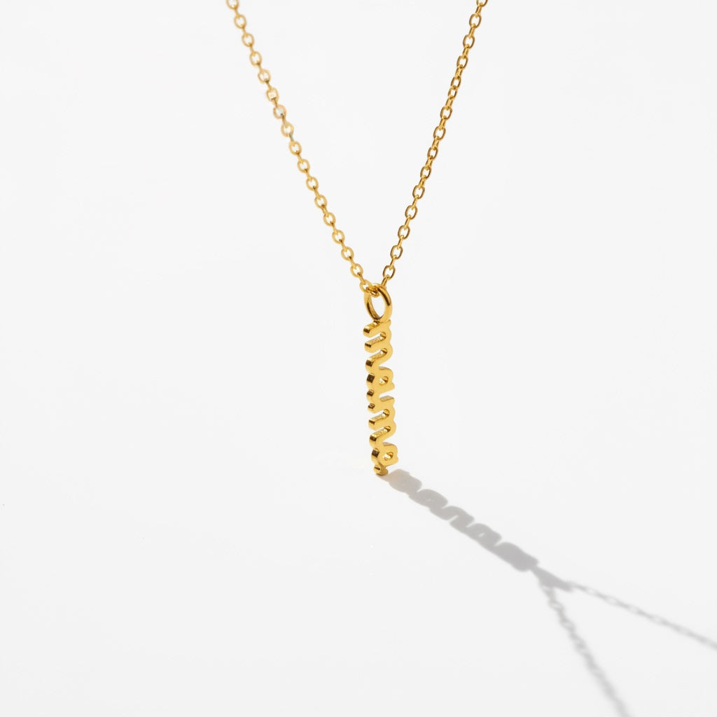 Minimalist gold necklace with vertical mama pendant on white background