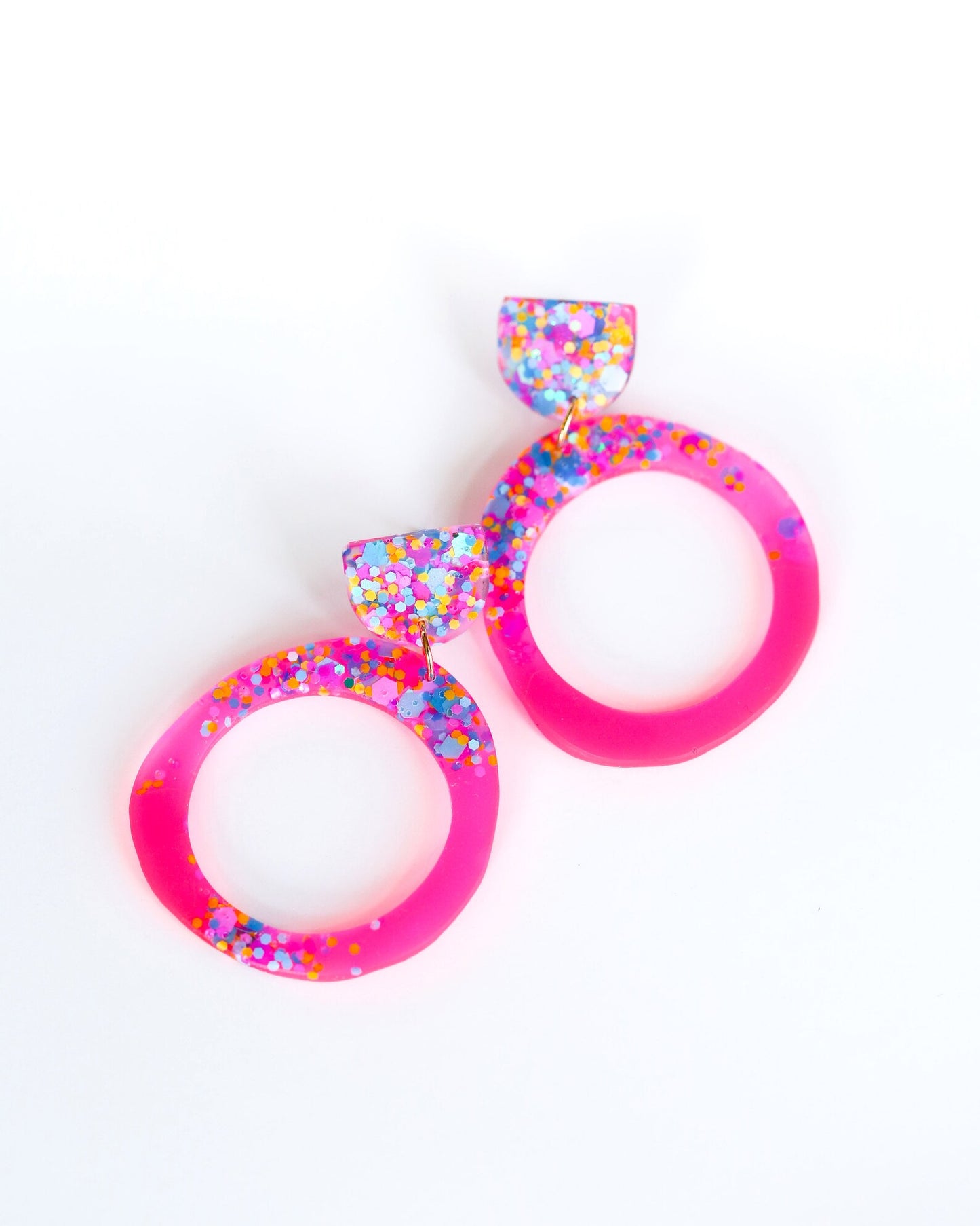 Pair of colorful earrings with pink and multicolor design on a white background