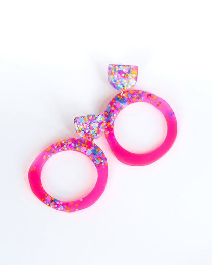 Pair of colorful earrings with pink and multicolor design on a white background