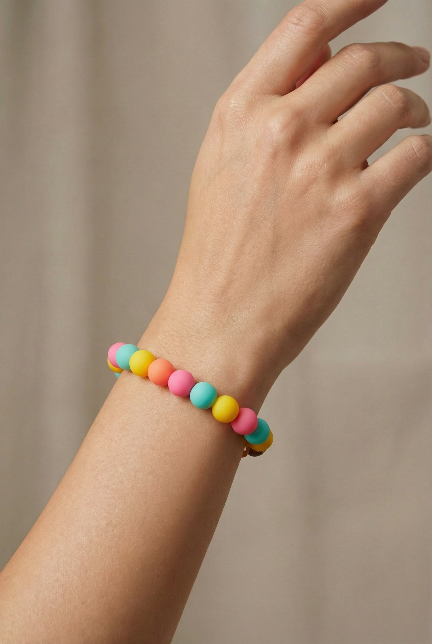 Colorful beaded bracelet on a wrist against a neutral background