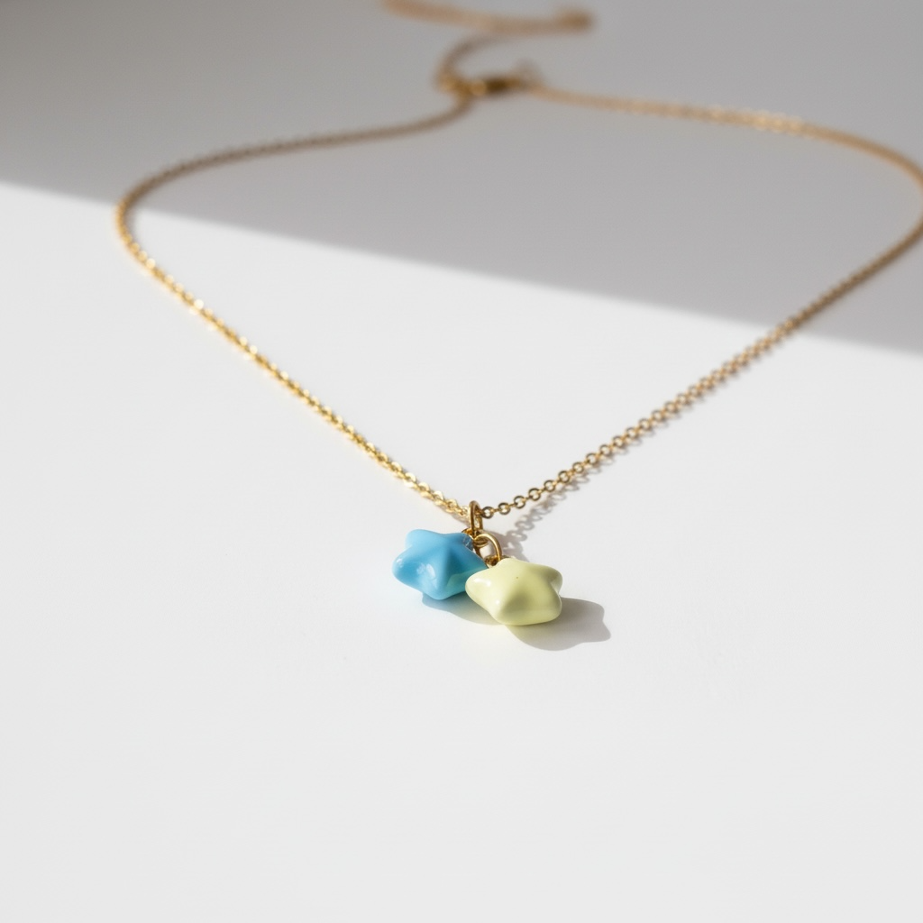 Gold necklace with blue and yellow star-shaped charms on a white background, minimalist jewelry