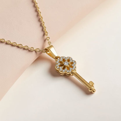 Gold key pendant necklace with sparkling gemstone accents on a delicate chain, minimalist style