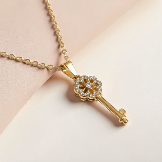 Gold key pendant necklace with sparkling gemstone accents on a delicate chain, minimalist style