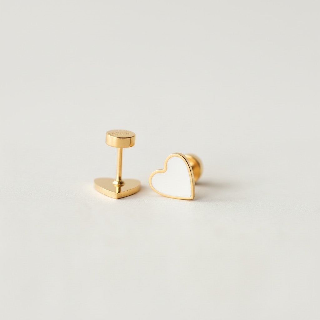 Gold flat back heart stud earrings with white enamel on a soft white background
