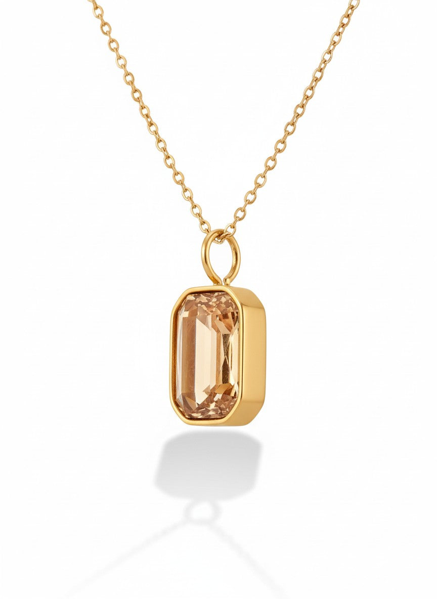 Gold chain necklace with rectangular crystal pendant on white background