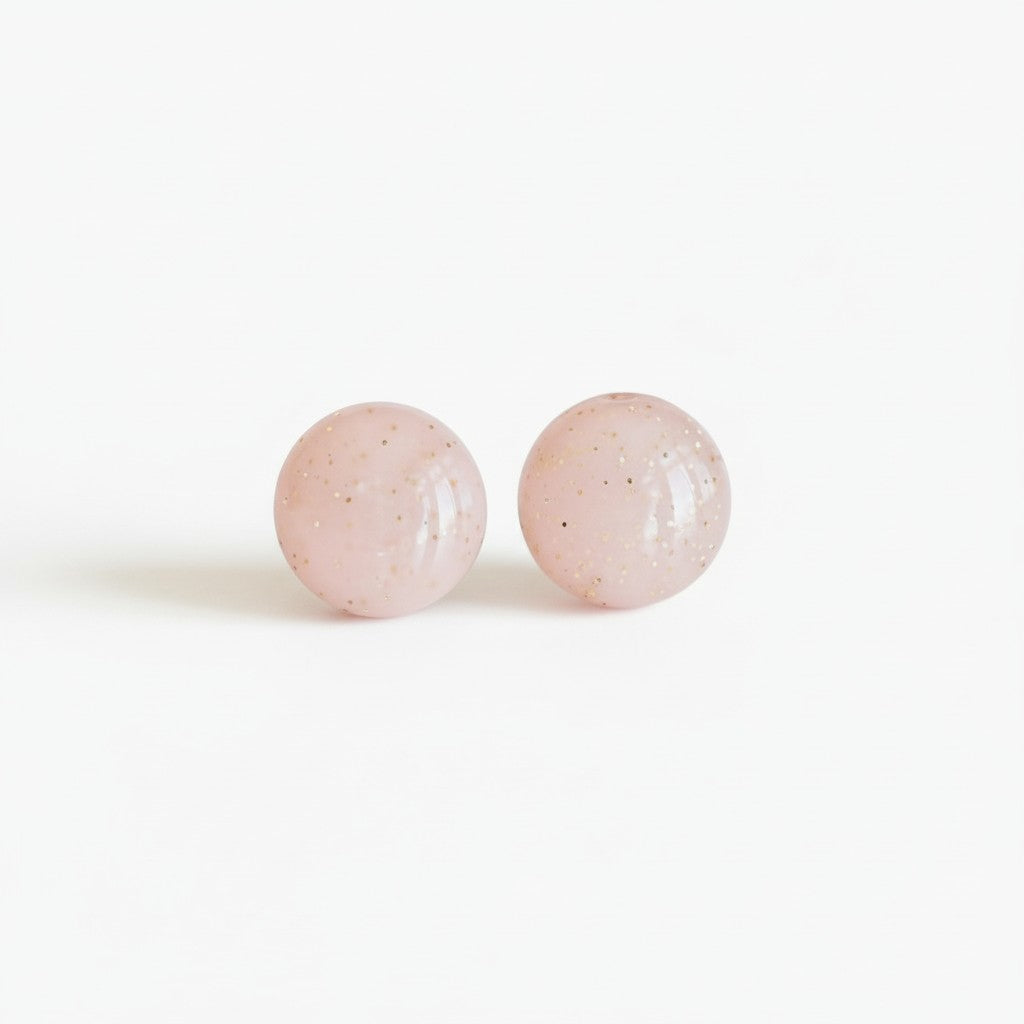 Minimalist pink round stud earrings with gold flecks on a white background