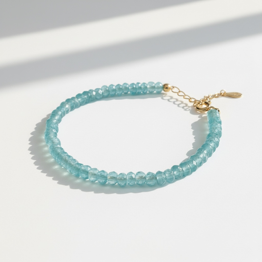 Handmade minimalist aquamarine beaded bracelet with gold clasp on white background