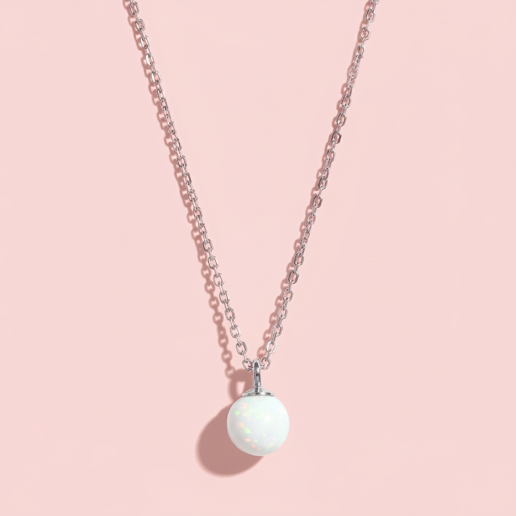 Minimalist silver chain necklace with a round white opal pendant on a pink background