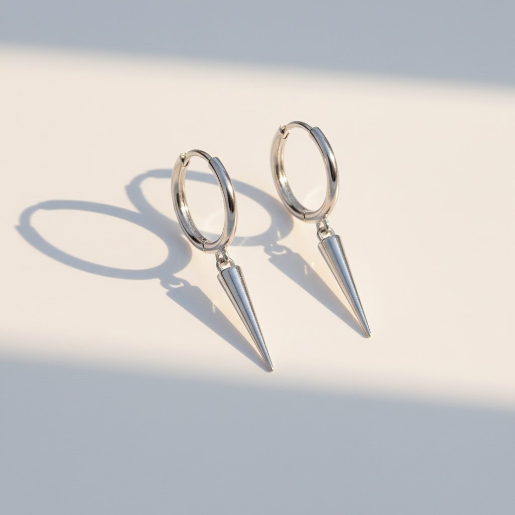 Minimalist silver hoop earrings with cone pendants on light background
