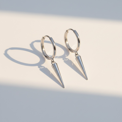 Minimalist silver hoop earrings with cone pendants on light background
