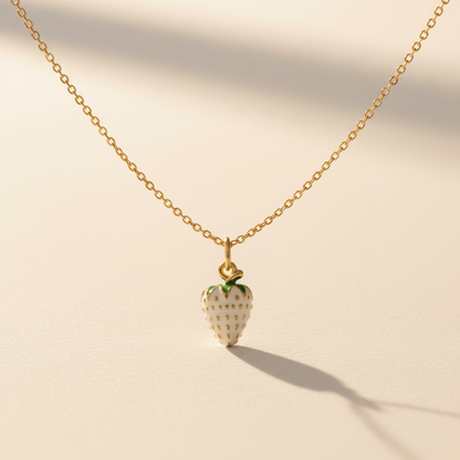 Gold chain necklace with a white strawberry pendant, minimalist jewelry on neutral background
