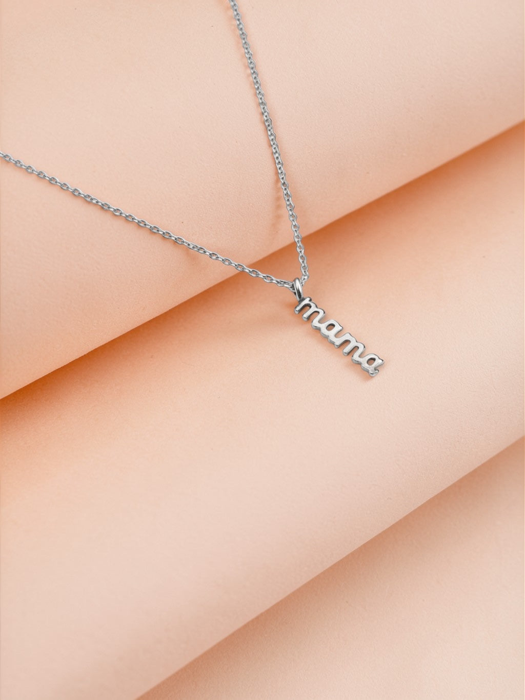 Silver mama necklace with delicate chain on soft beige background