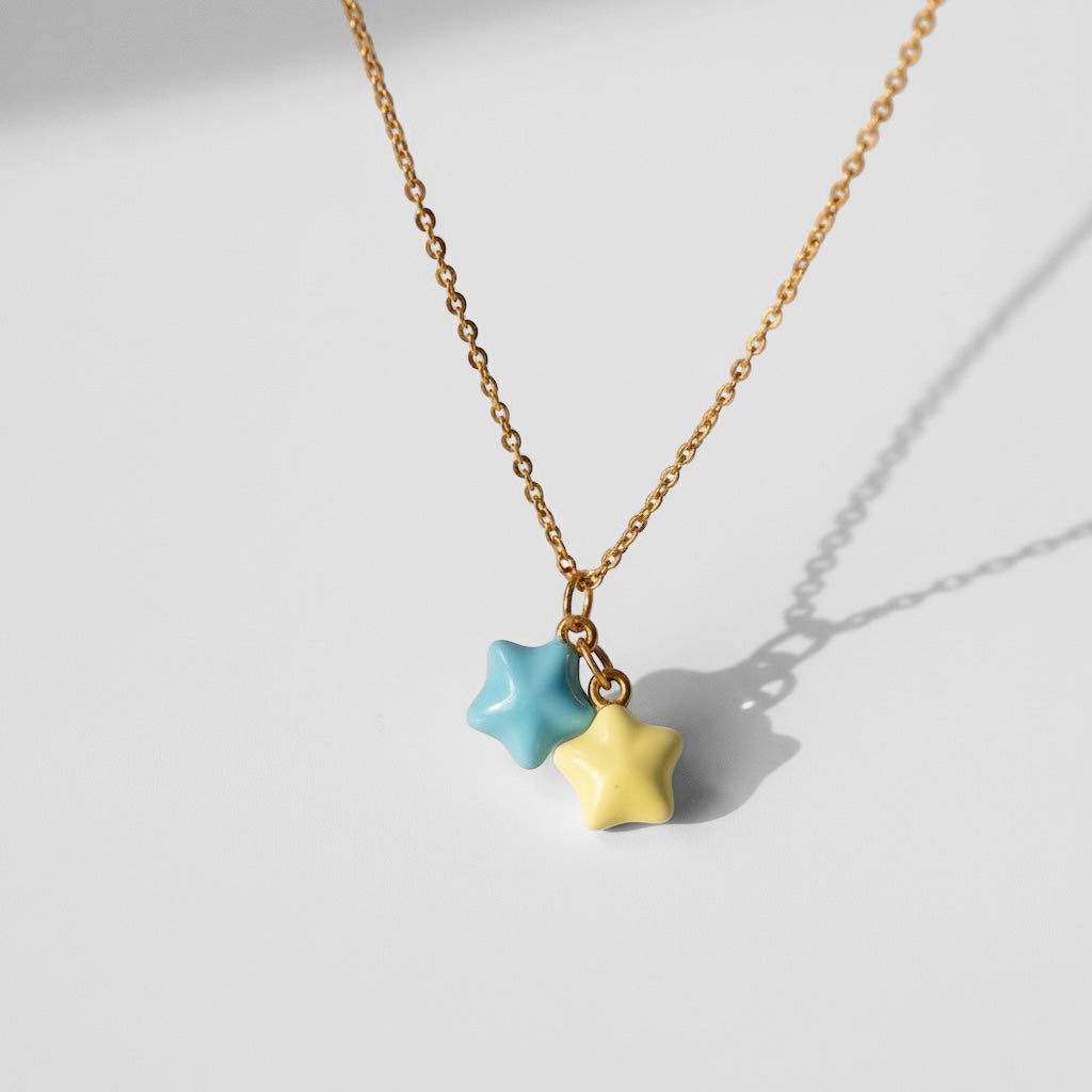 Gold necklace with blue and yellow star charms on a white background