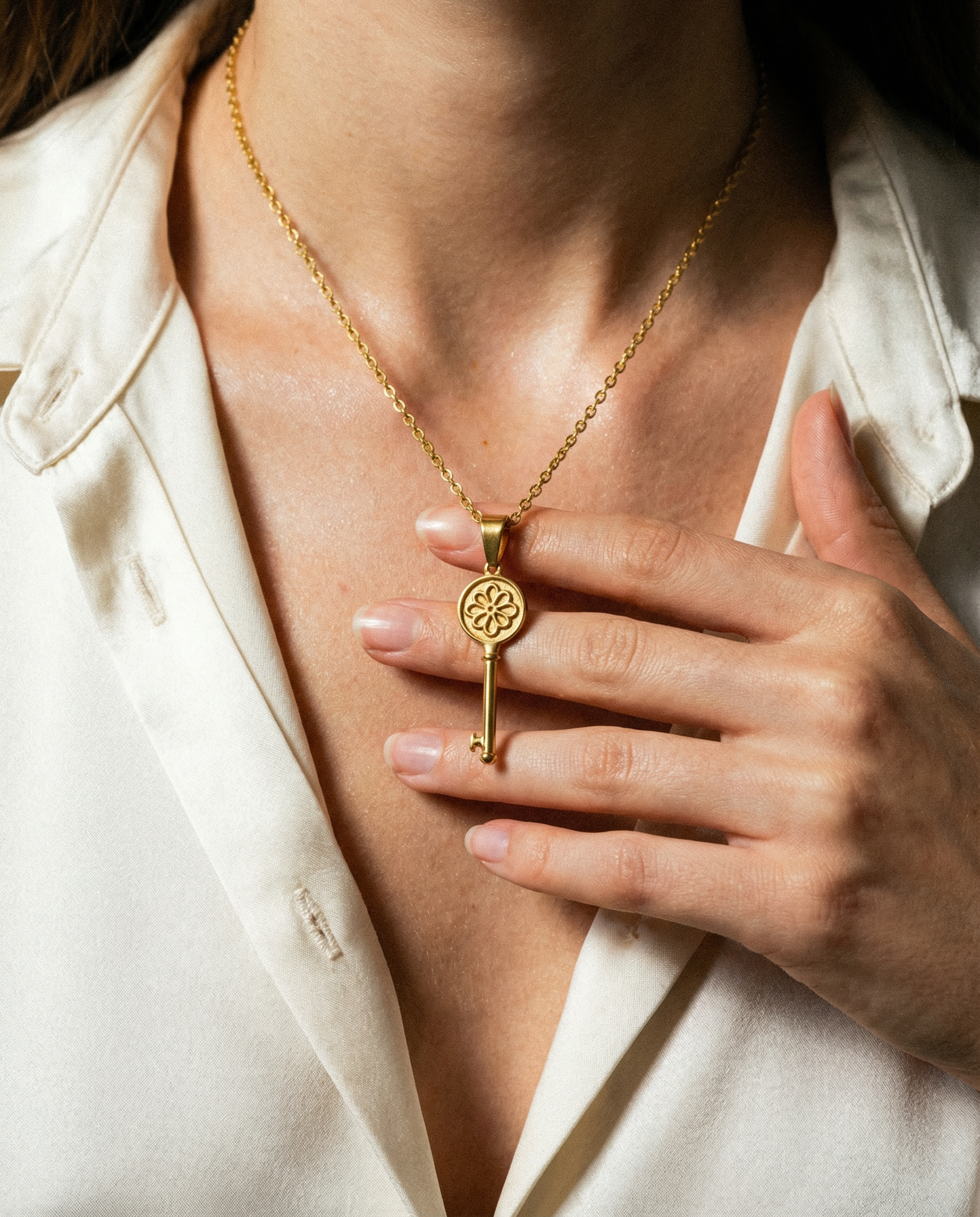 Woman wearing gold key-shaped stainless steel charm necklace over cream blouse