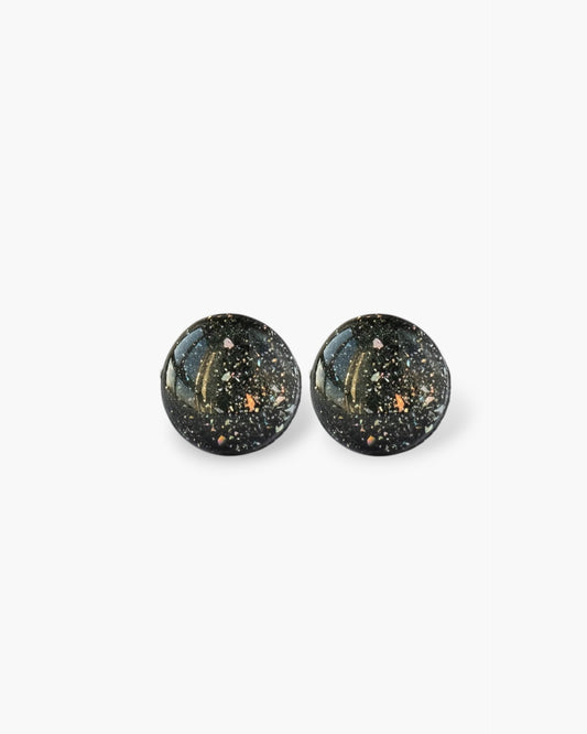 Pair of black round earrings with speckled design on a white background