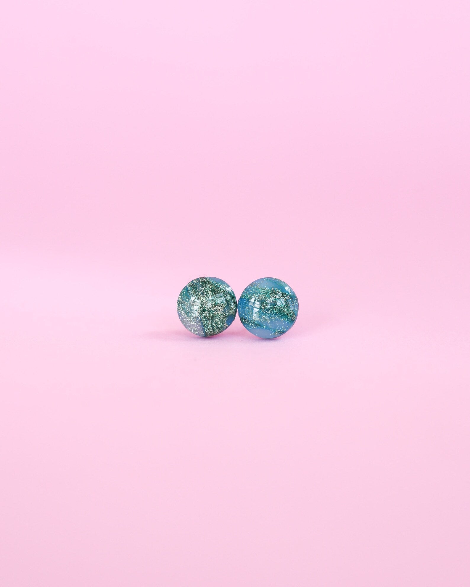 Pair of turquoise earrings on a pink background