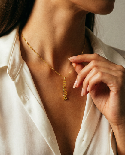 Woman wearing gold stainless steel 'mama' charm necklace with white blouse
