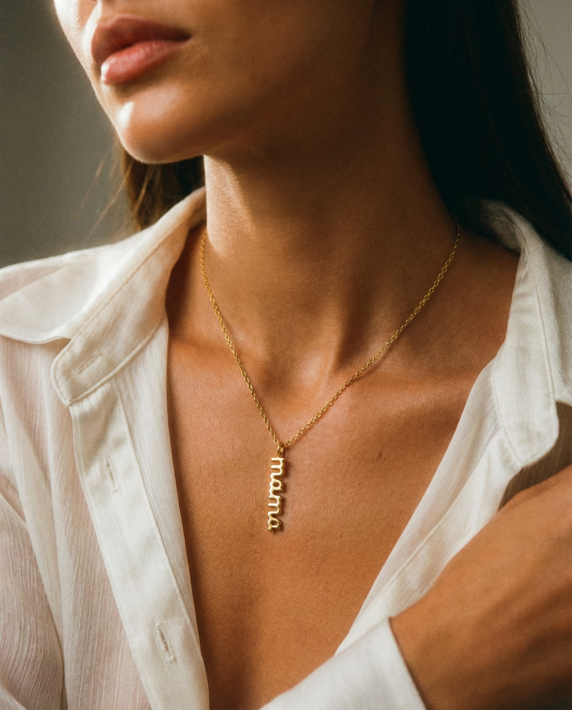 Woman wearing gold stainless steel 'mama' charm necklace with minimalist style