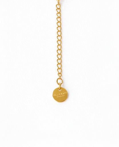 Gold chain necklace with a round pendant on a white background