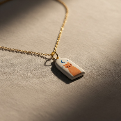 Necklace with a pendant featuring a cat design on a beige surface