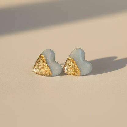 Sky blue heart stud earrings with gold leaf accent on neutral background