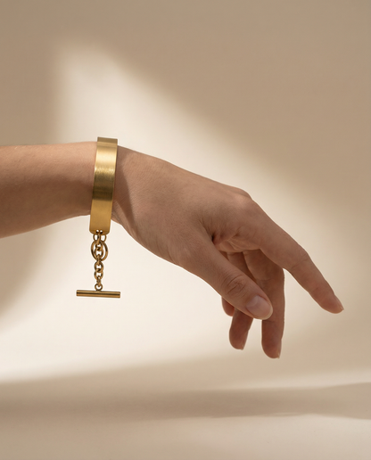 Gold stainless steel cuff bracelet with chain closure on wrist, minimalist jewelry