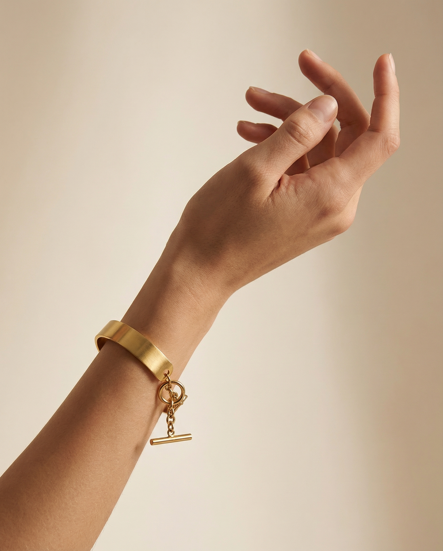 Gold stainless steel cuff bracelet with chain closure on wrist, minimalist jewelry