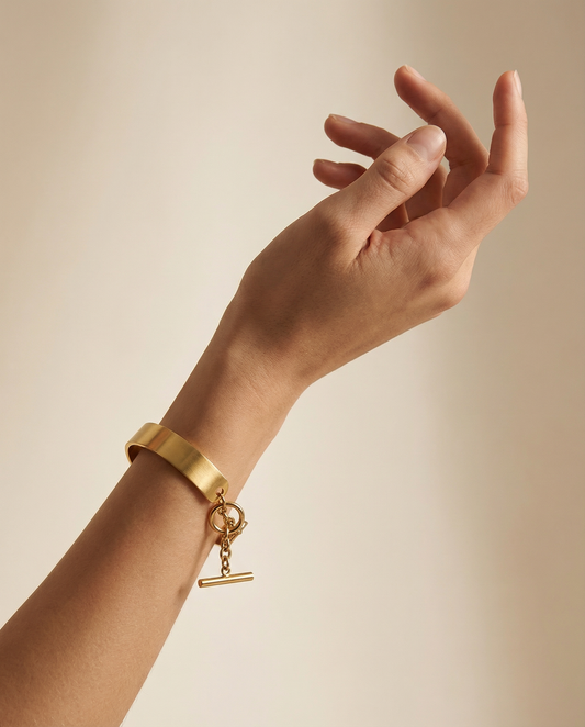 Gold stainless steel cuff bracelet with chain closure on wrist, minimalist jewelry