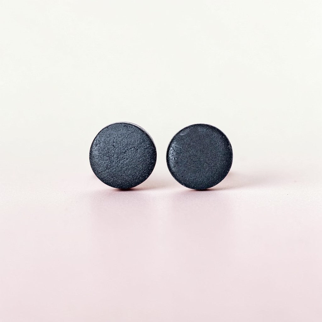 Minimalist matte black stud earrings on a light background