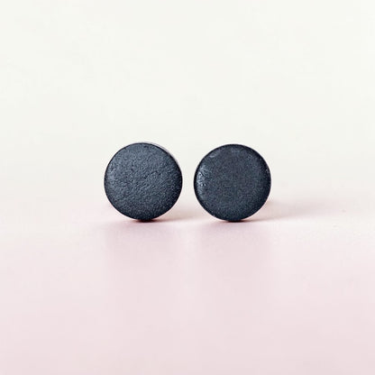 Minimalist matte black stud earrings on a light background