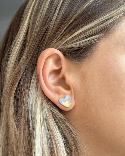 Handmade heart-shaped blue and gold stud earring worn on ear, minimalist jewelry