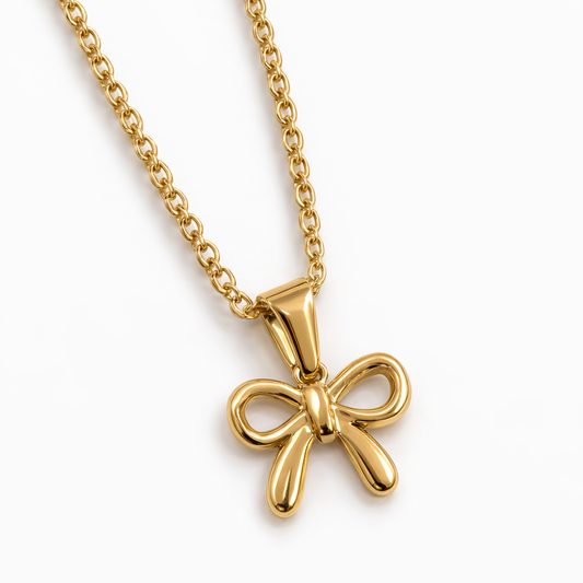 Gold bow-shaped pendant on a chain against a white background