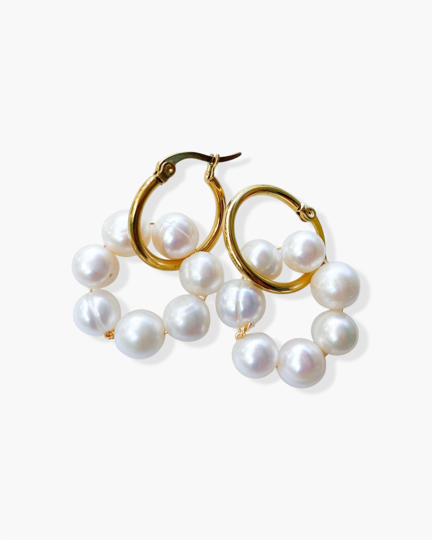 Gold hoop earrings with pearl beads on a white background
