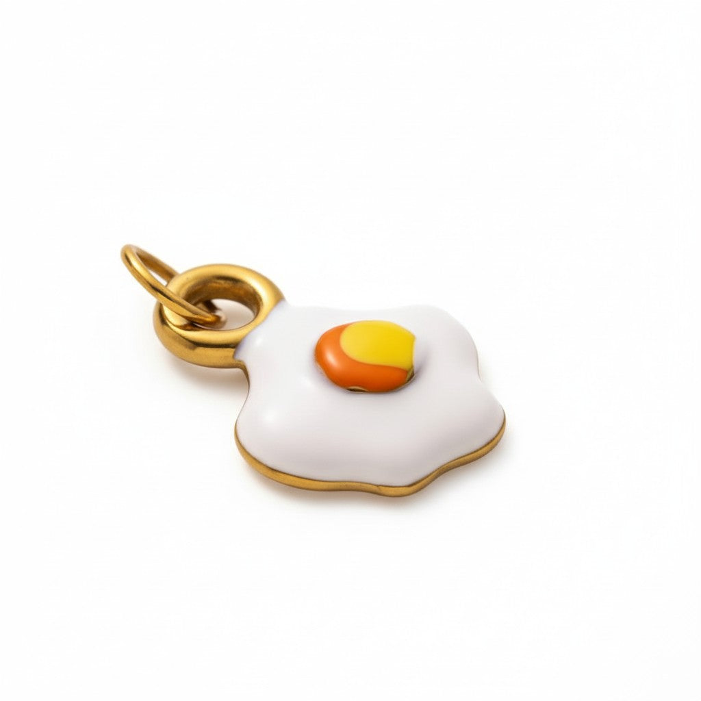 Gold-tone fried egg charm pendant with white enamel and yellow-orange yolk detail