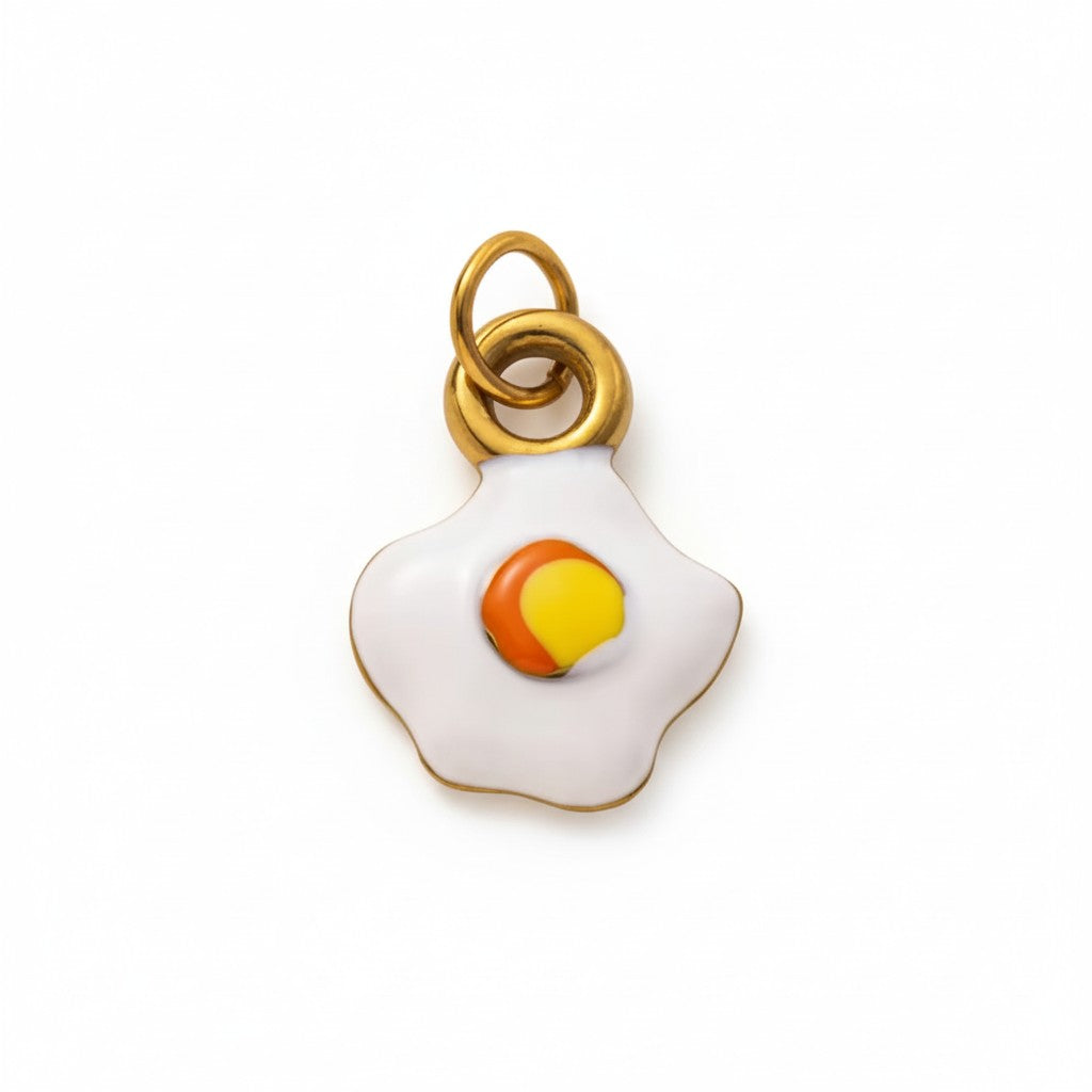 Gold and enamel fried egg charm pendant with minimalist design on white background