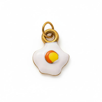 Gold and enamel fried egg charm pendant with minimalist design on white background