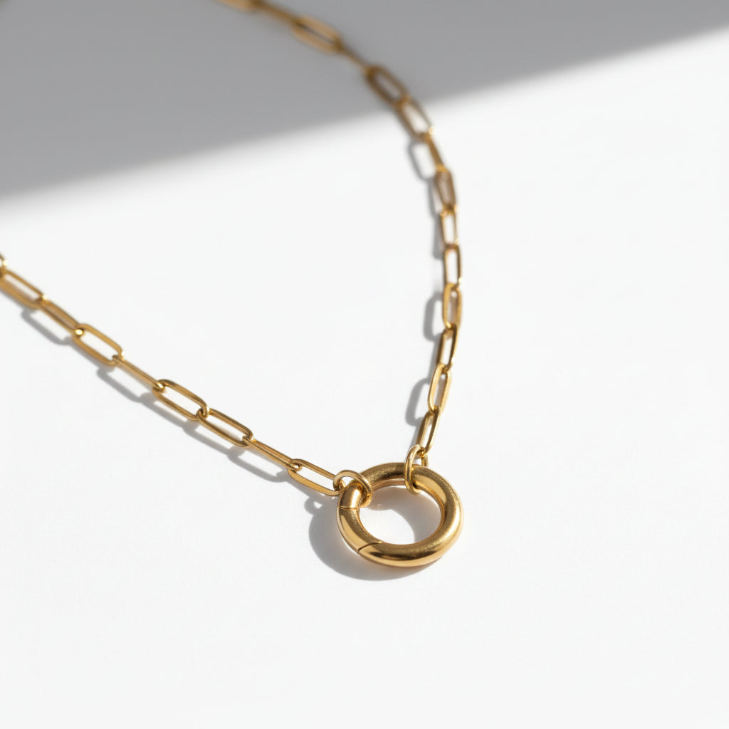 Minimalist gold chain necklace with a circular pendant on a white background
