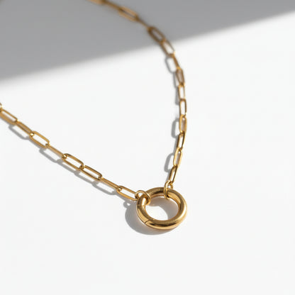 Minimalist gold chain necklace with a circular pendant on a white background