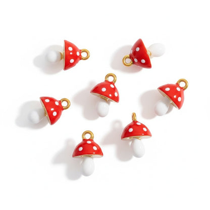 Red and white enamel mushroom charms with gold trim arranged on a white background